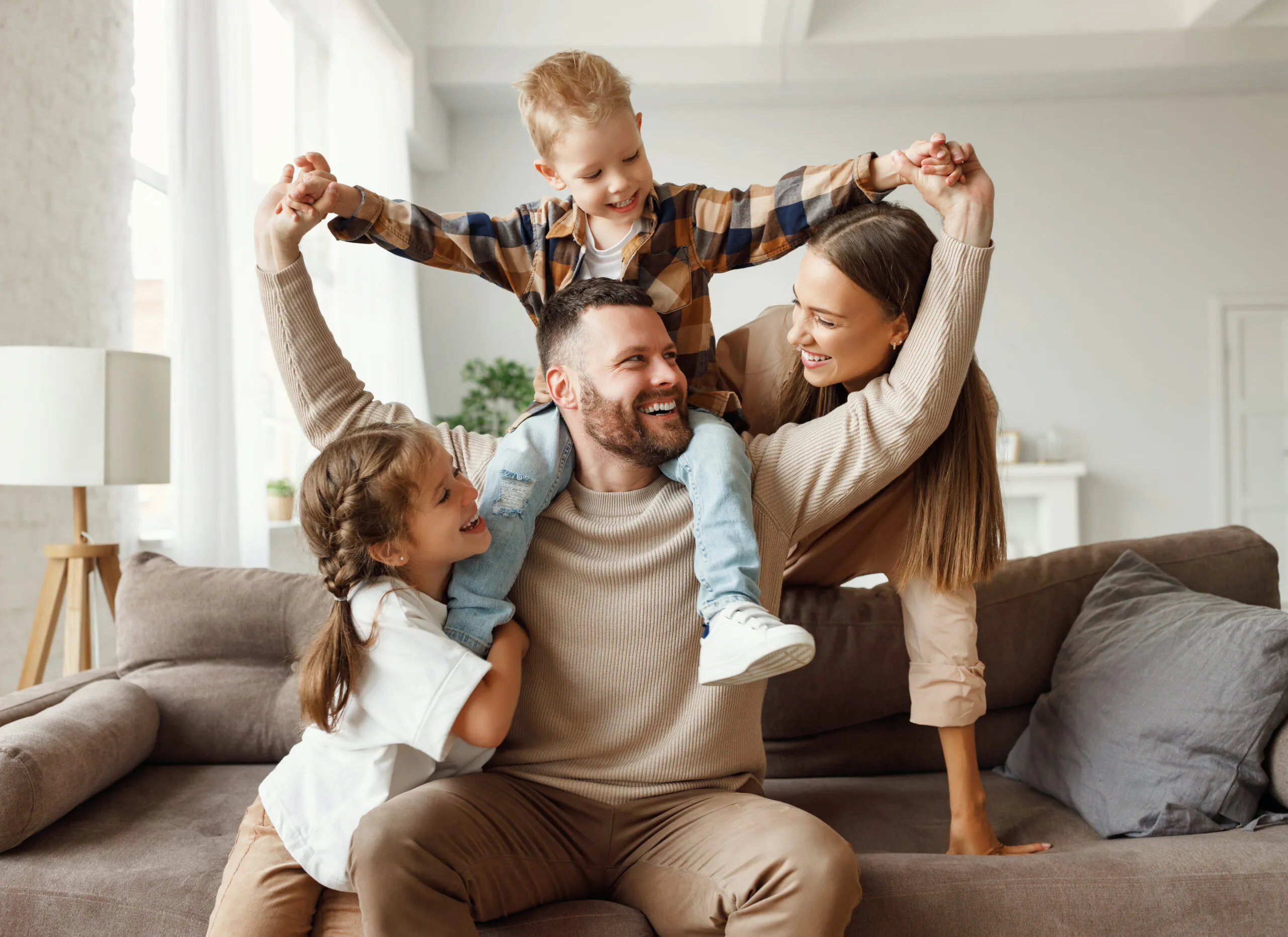 Family indoors with a child sitting on an adult’s shoulders in a living room | Lafford Group