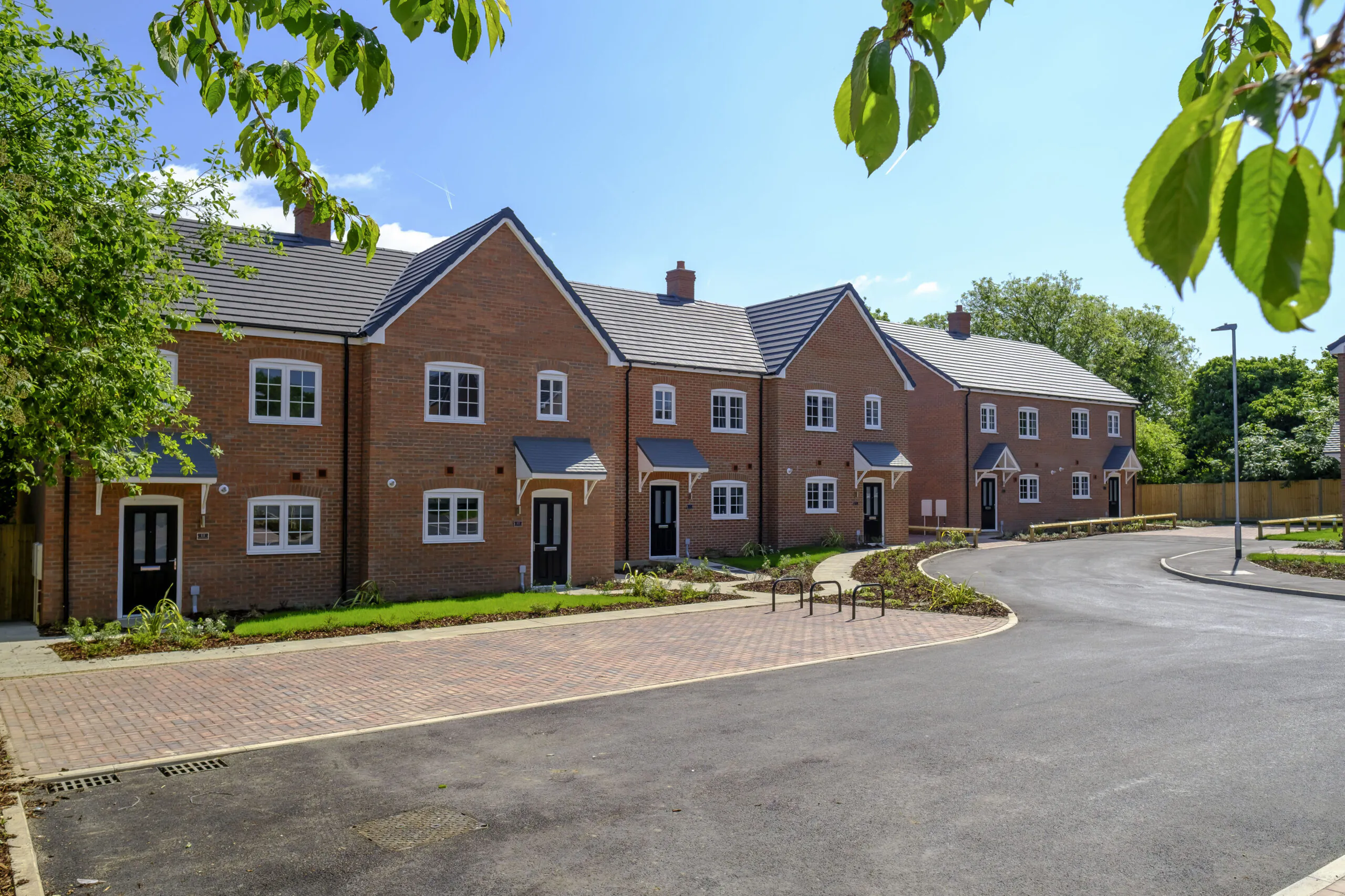Completed new brick homes at Old Quarry Close, Metheringham along a curved street with fresh landscaping and a clear blue sky | Lafford Group