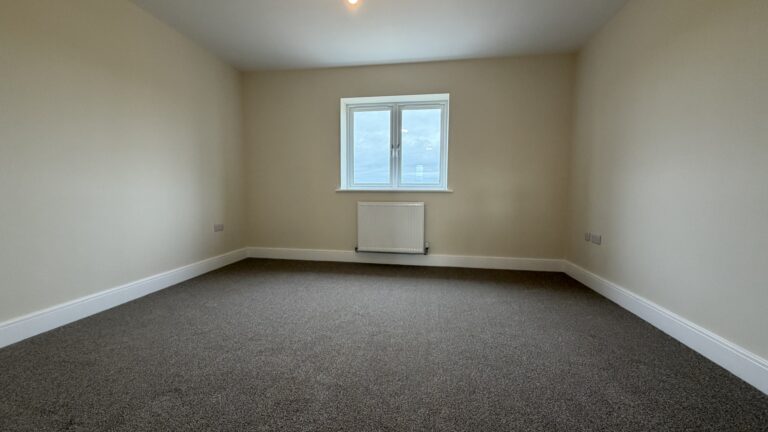 The Waltham at Petrella Place – Bedroom 1 with neutral décor, fitted carpet, double-glazed window and radiator beneath.