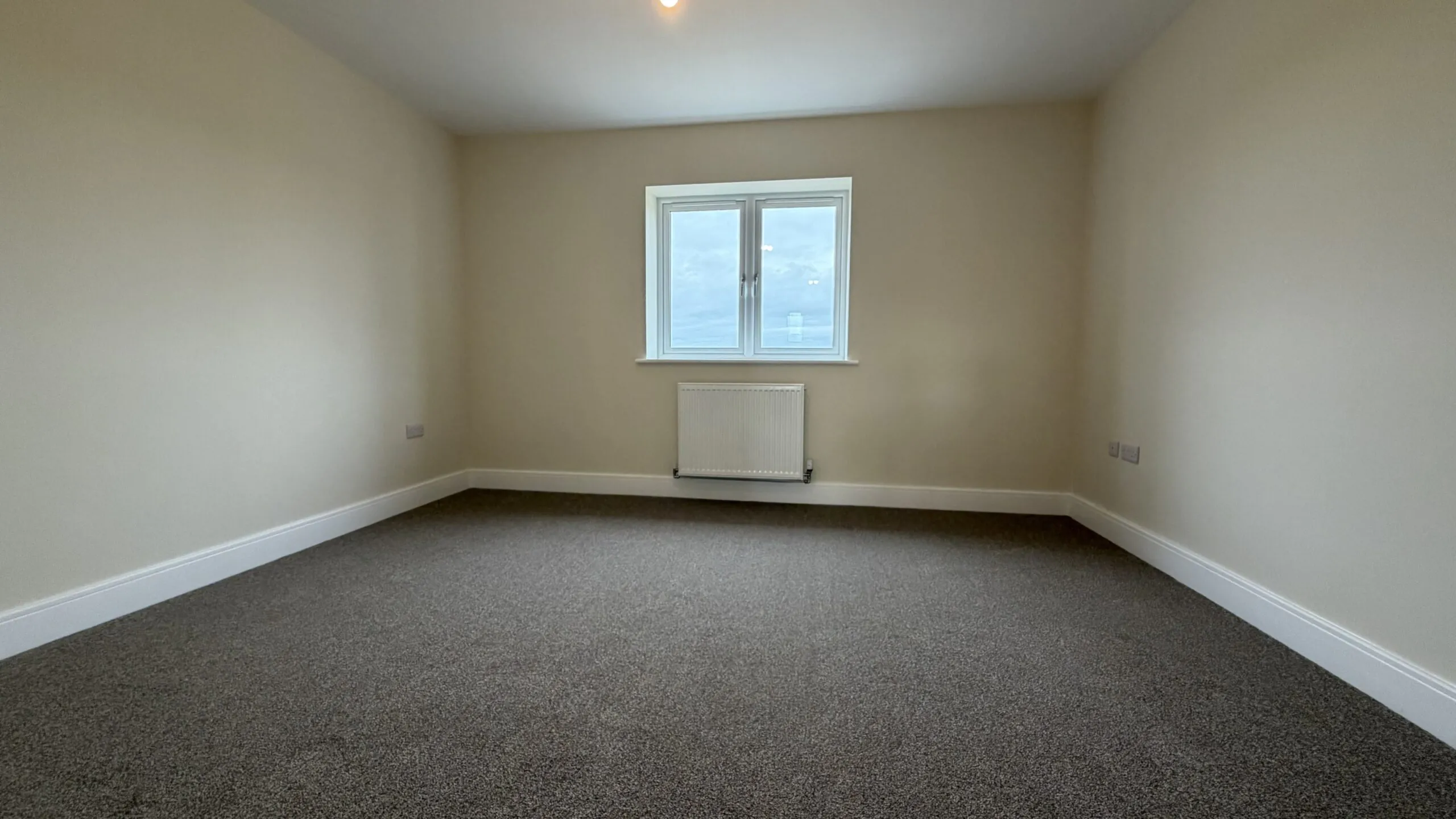 The Waltham at Petrella Place – Bedroom 1 with neutral décor, fitted carpet, double-glazed window and radiator beneath.