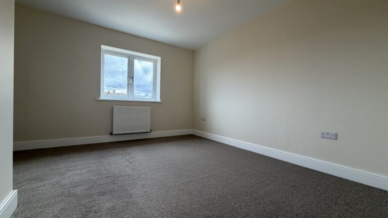 The Waltham at Petrella Place – Bedroom 2 with neutral décor, fitted carpet, double-glazed window and radiator beneath.