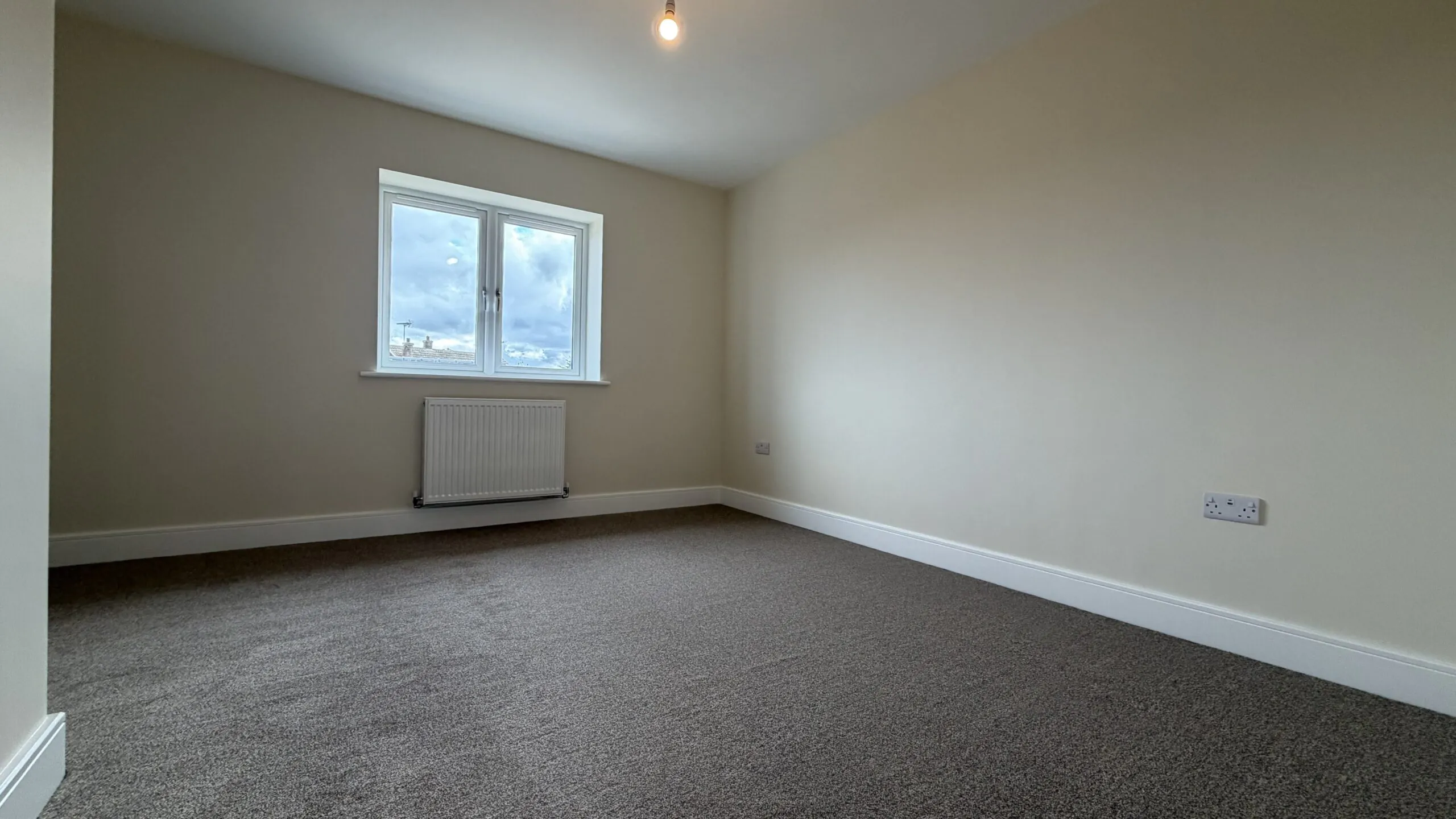 The Waltham at Petrella Place – Bedroom 2 with neutral décor, fitted carpet, double-glazed window and radiator beneath.