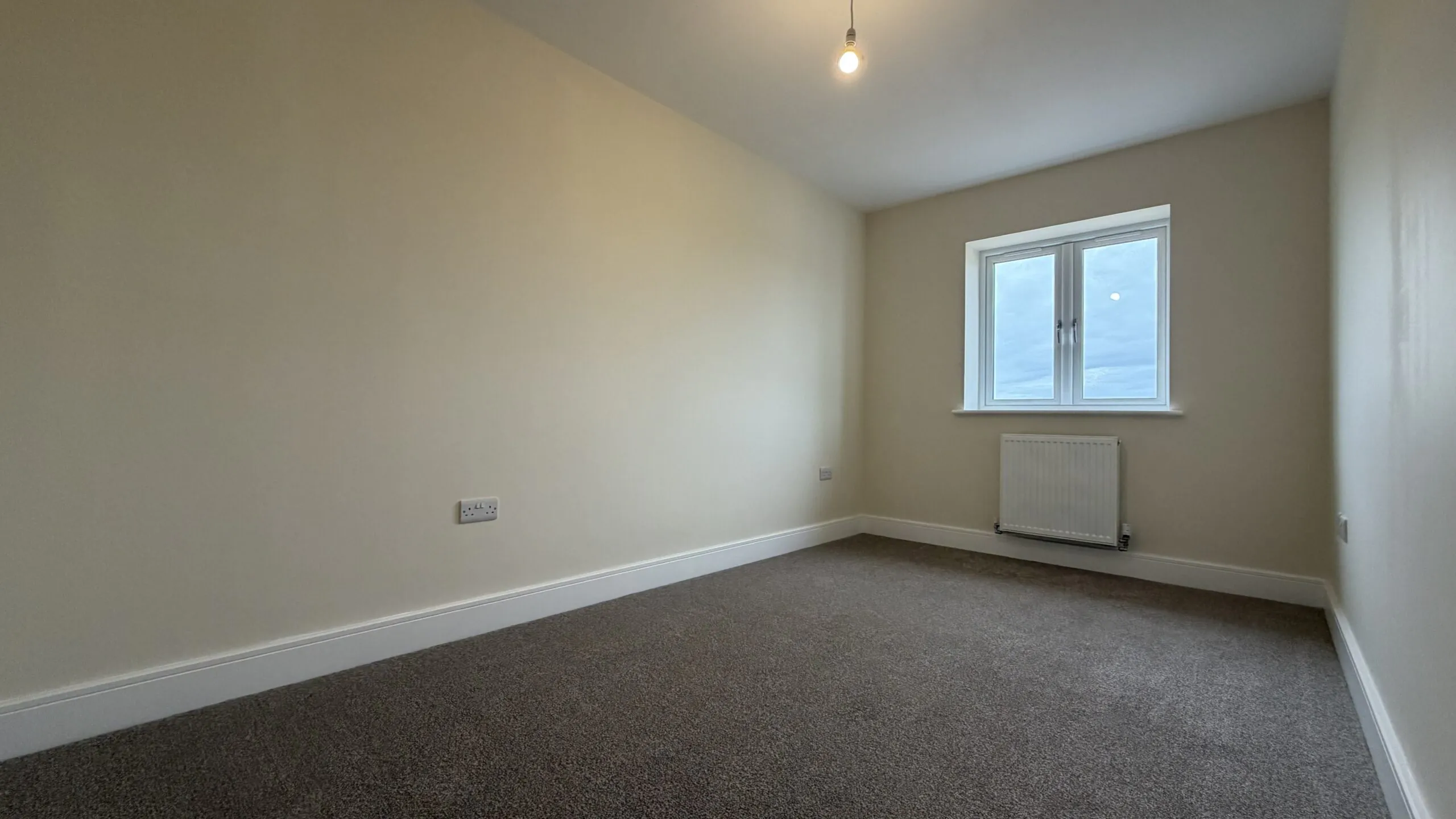 The Caister at Petrella Place – Bedroom 2 with neutral décor, fitted carpet, double-glazed window and radiator beneath.