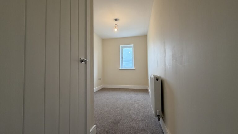 The Caister at Petrella Place – Bedroom 3 with fitted carpet, neutral décor, a single window at the far end and a wall-mounted radiator.