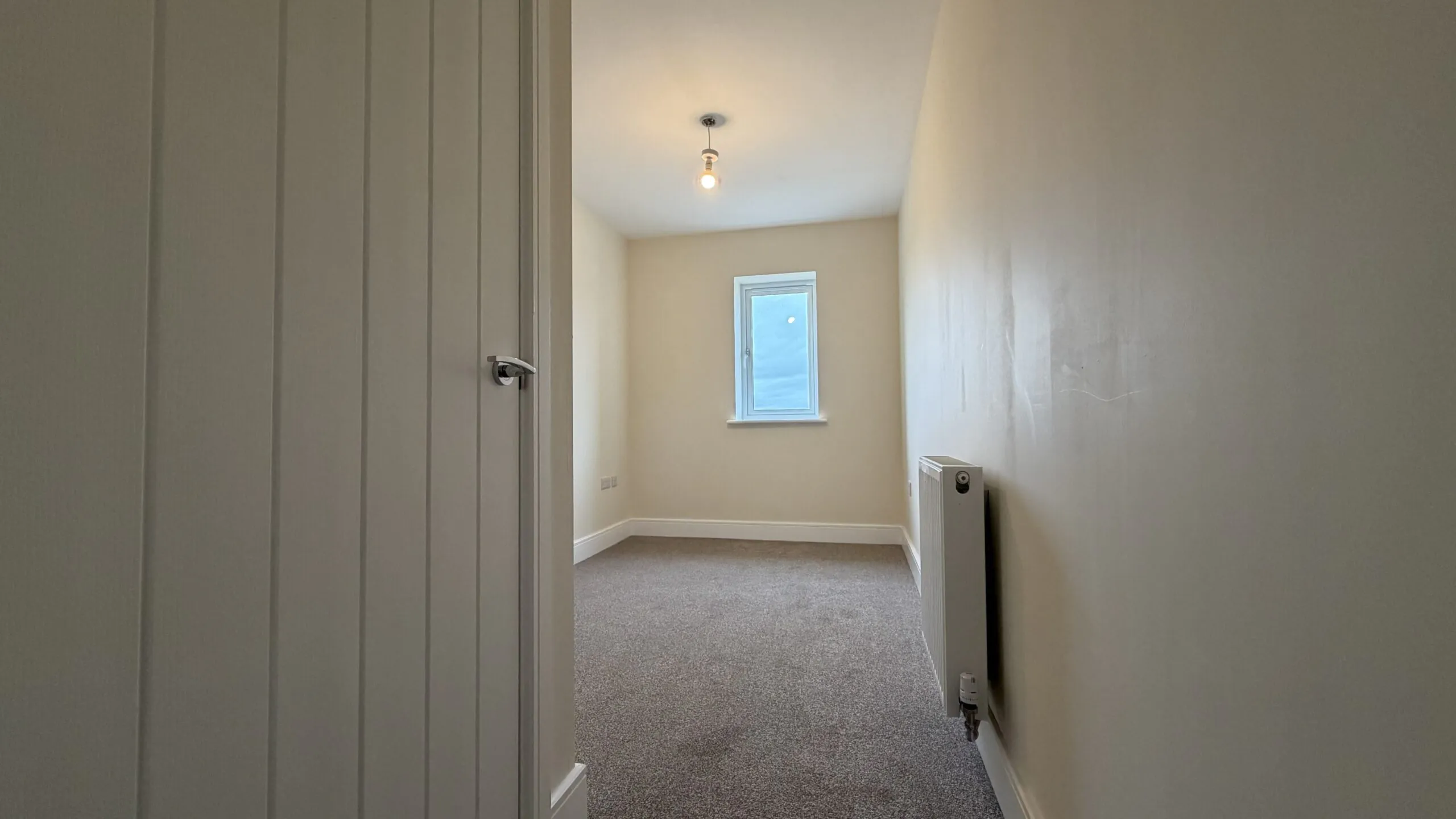 The Caister at Petrella Place – Bedroom 3 with fitted carpet, neutral décor, a single window at the far end and a wall-mounted radiator.