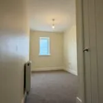 The Caister at Petrella Place – Bedroom 3 with neutral décor, fitted carpet, a window at the far end and radiator, viewed from the doorway.