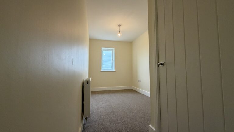 The Caister at Petrella Place – Bedroom 3 with neutral décor, fitted carpet, a window at the far end and radiator, viewed from the doorway.