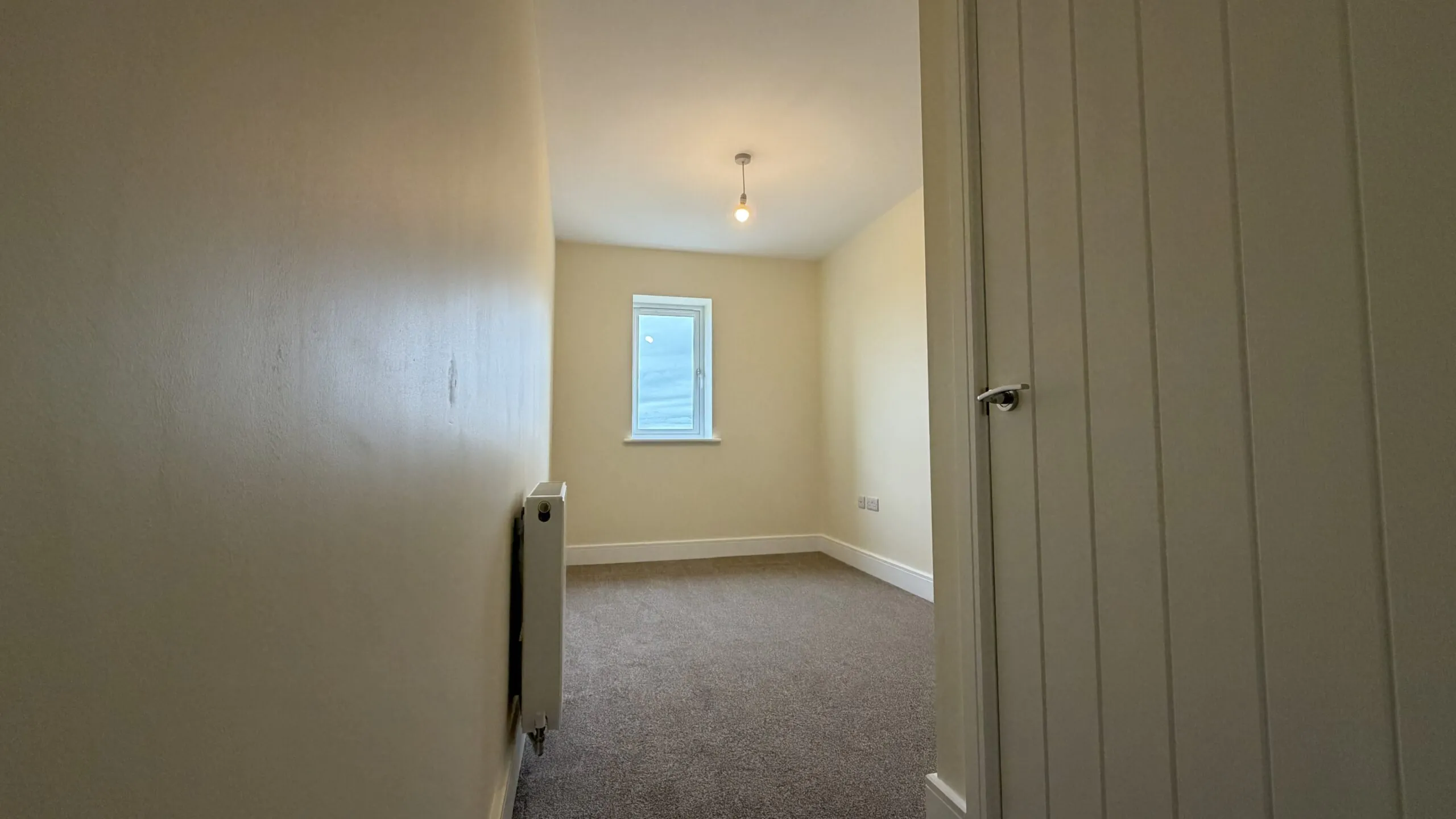 The Caister at Petrella Place – Bedroom 3 with neutral décor, fitted carpet, a window at the far end and radiator, viewed from the doorway.