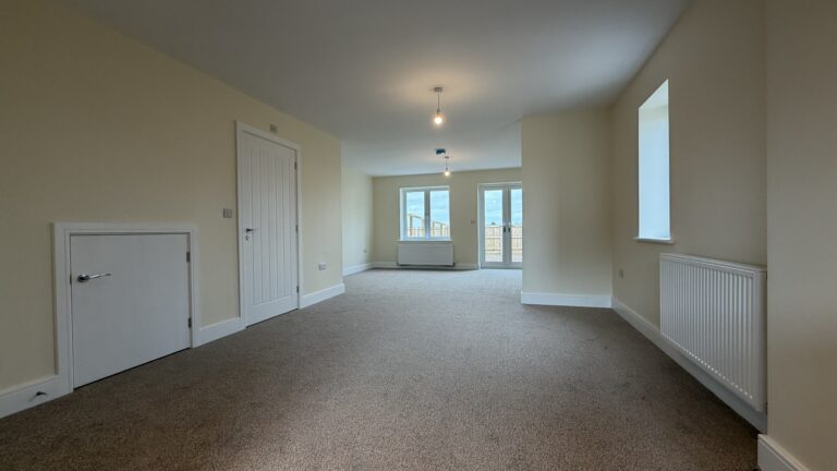 The Caister at Petrella Place – open-plan dining area looking toward the living space with neutral décor, carpeted floor, and window and French doors to the rear garden.