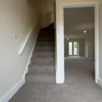 The Caister at Petrella Place – entrance hallway with carpeted stairs, neutral décor and doorway through to the living area with garden doors beyond.