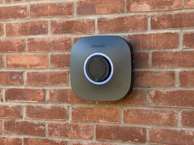 Rolec electric vehicle car charger mounted on a red brick wall at Petrella Place, with a circular charging socket and illuminated ring.