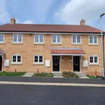 Exterior view of Plots 6, 7 and 8 at Beacon Hollow, showing three brand-new terraced homes with brick elevations, front gardens and private entrances.