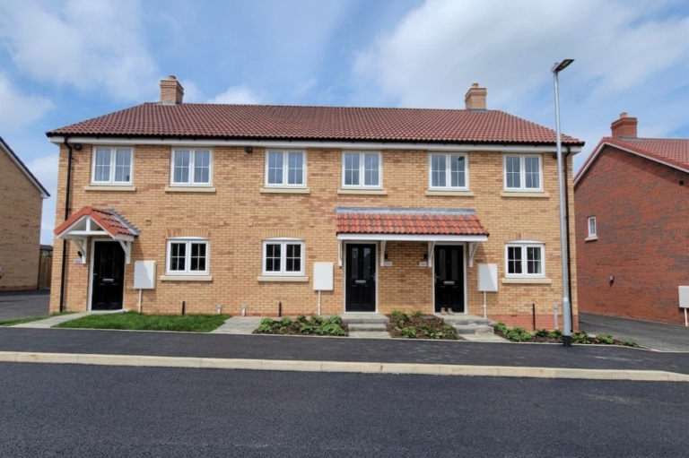 Exterior view of Plots 6, 7 and 8 at Beacon Hollow, showing three brand-new terraced homes with brick elevations, front gardens and private entrances.