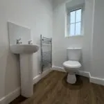 Ground floor cloakroom at 34 Warwick Drive featuring a WC, pedestal wash basin, heated chrome towel rail and frosted window providing natural light.