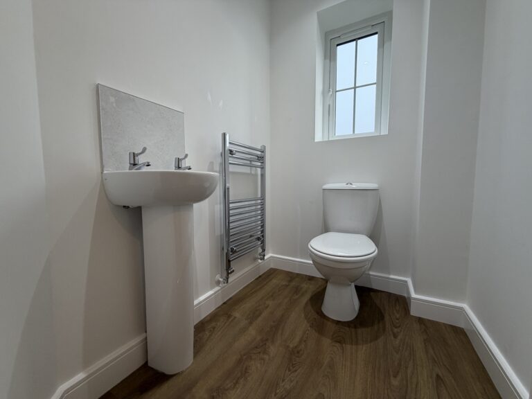 Ground floor cloakroom at 34 Warwick Drive featuring a WC, pedestal wash basin, heated chrome towel rail and frosted window providing natural light.
