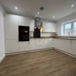 Contemporary fitted kitchen at 34 Warwick Drive featuring modern white cabinetry, wood-effect worktops, integrated AEG appliances and ample space for dining.