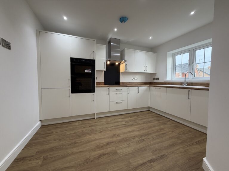 Contemporary fitted kitchen at 34 Warwick Drive featuring modern white cabinetry, wood-effect worktops, integrated AEG appliances and ample space for dining.
