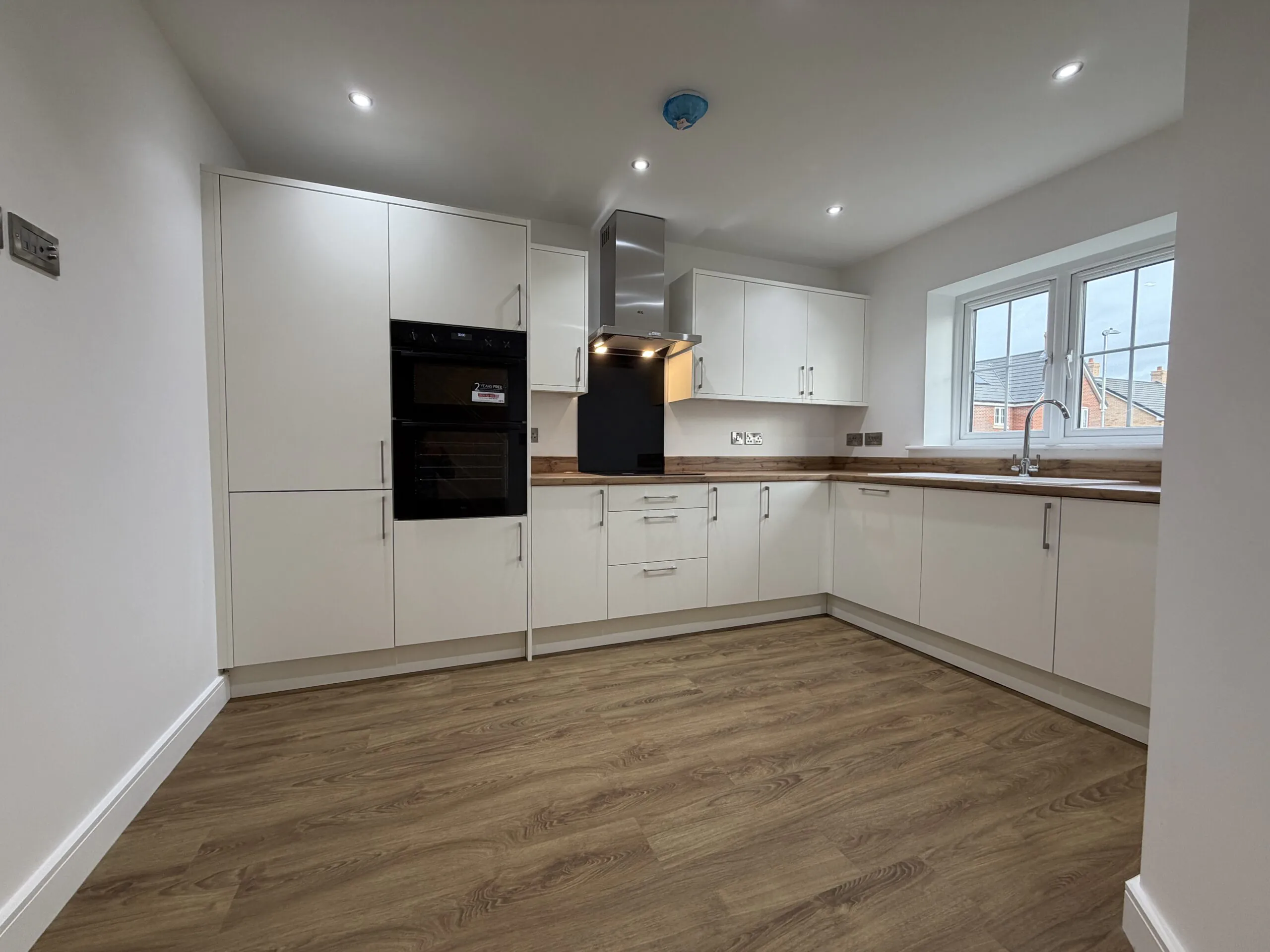 Contemporary fitted kitchen at 34 Warwick Drive featuring modern white cabinetry, wood-effect worktops, integrated AEG appliances and ample space for dining.