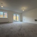 Spacious living room at 34 Warwick Drive featuring soft carpeting, generous floor space, a rear-facing window and French doors opening onto the enclosed garden.