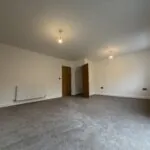 Spacious living room at 34 Warwick Drive featuring soft grey carpeting, a bright dual-aspect layout and ample space for both lounge and dining furniture.