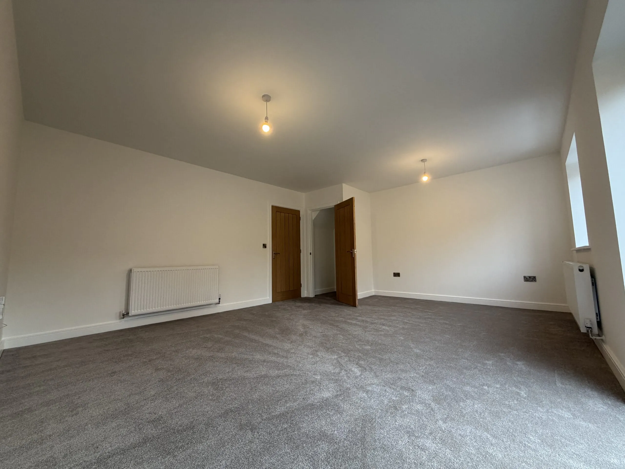 Spacious living room at 34 Warwick Drive featuring soft grey carpeting, a bright dual-aspect layout and ample space for both lounge and dining furniture.