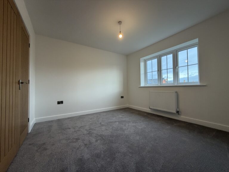 Principal bedroom at 34 Warwick Drive featuring soft grey carpeting, multiple windows providing excellent natural light and generous floor space for a double bed and bedroom furniture.