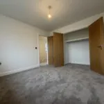 Principal bedroom at 34 Warwick Drive featuring soft grey carpeting, dual windows allowing plenty of natural light and generous space for a double bed, wardrobes and additional bedroom furniture.