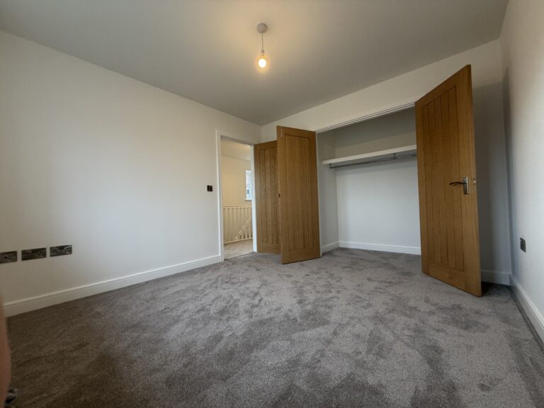 Principal bedroom at 34 Warwick Drive featuring soft grey carpeting, dual windows allowing plenty of natural light and generous space for a double bed, wardrobes and additional bedroom furniture.