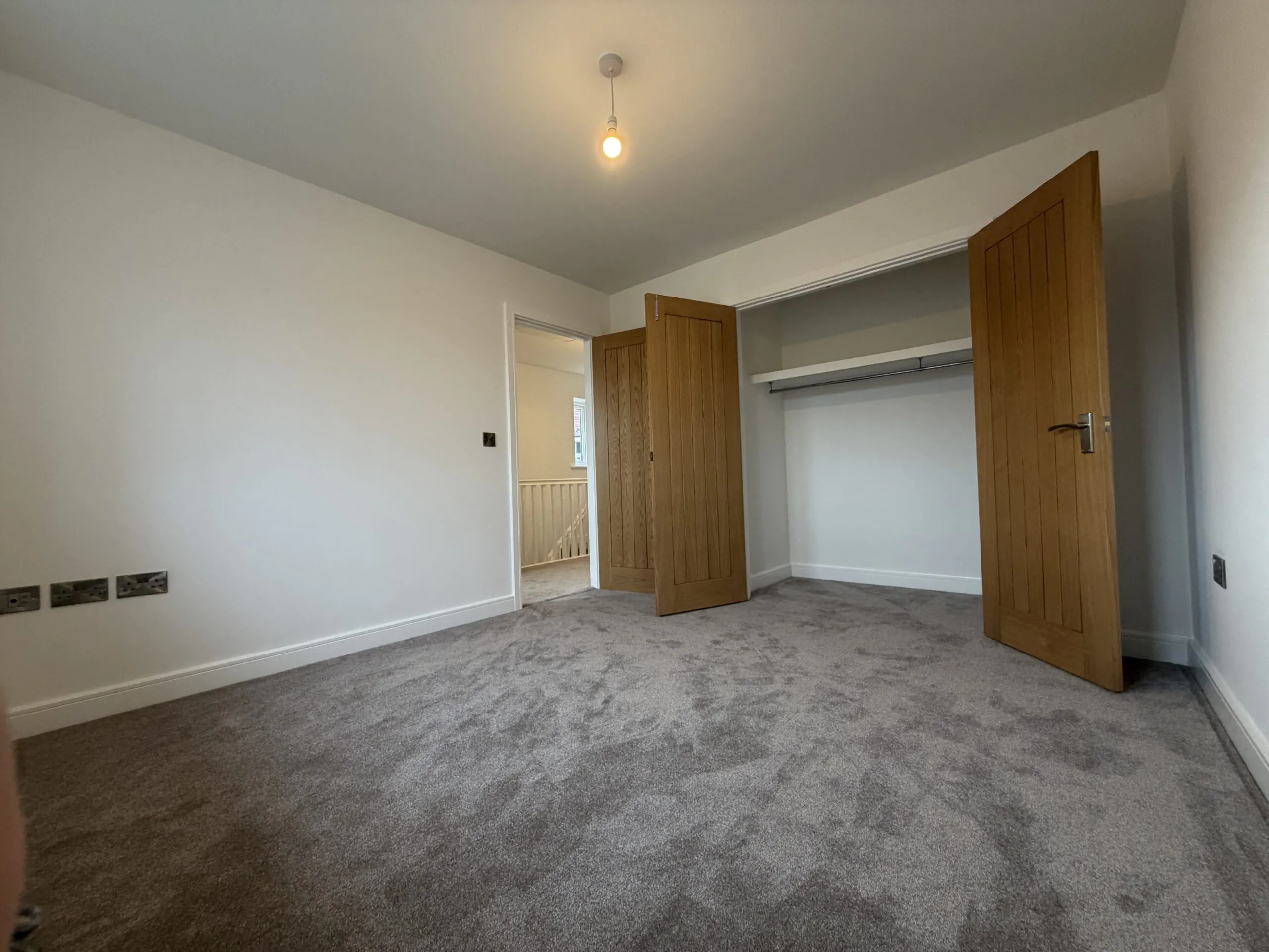 Principal bedroom at 34 Warwick Drive featuring soft grey carpeting, dual windows allowing plenty of natural light and generous space for a double bed, wardrobes and additional bedroom furniture.