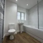 Family bathroom at 34 Warwick Drive featuring a contemporary white suite, bath with shower and glazed screen, pedestal wash basin, WC and chrome heated towel rail.