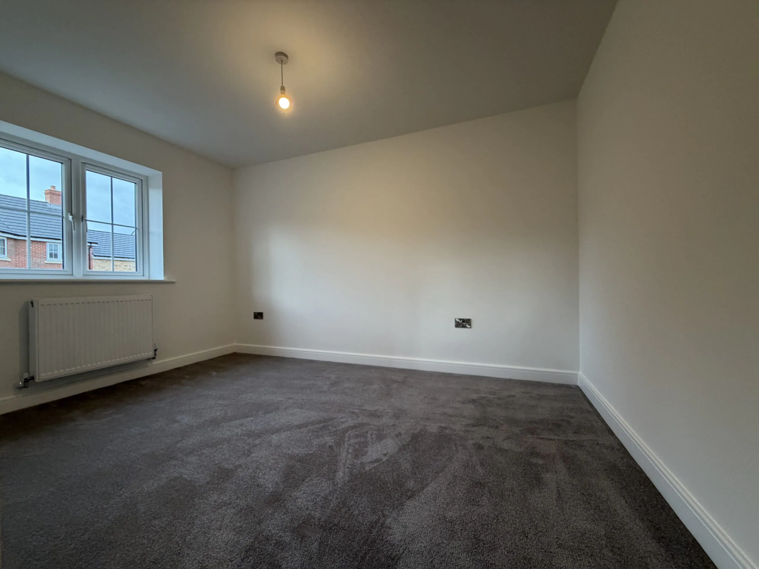 Bedroom Two at 34 Warwick Drive featuring soft grey carpeting, a rear-facing window providing natural light and a spacious layout suitable for a double bed and additional furniture.