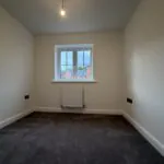 Bedroom Three at 34 Warwick Drive featuring soft grey carpeting, neutral décor, a front-facing window and a versatile layout suitable for a child's bedroom, nursery or home office.